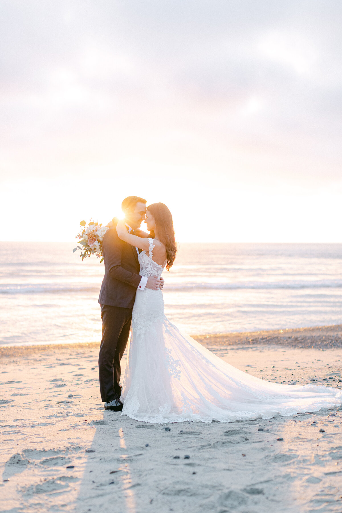 Bride and groom embracing on the beach at sunset