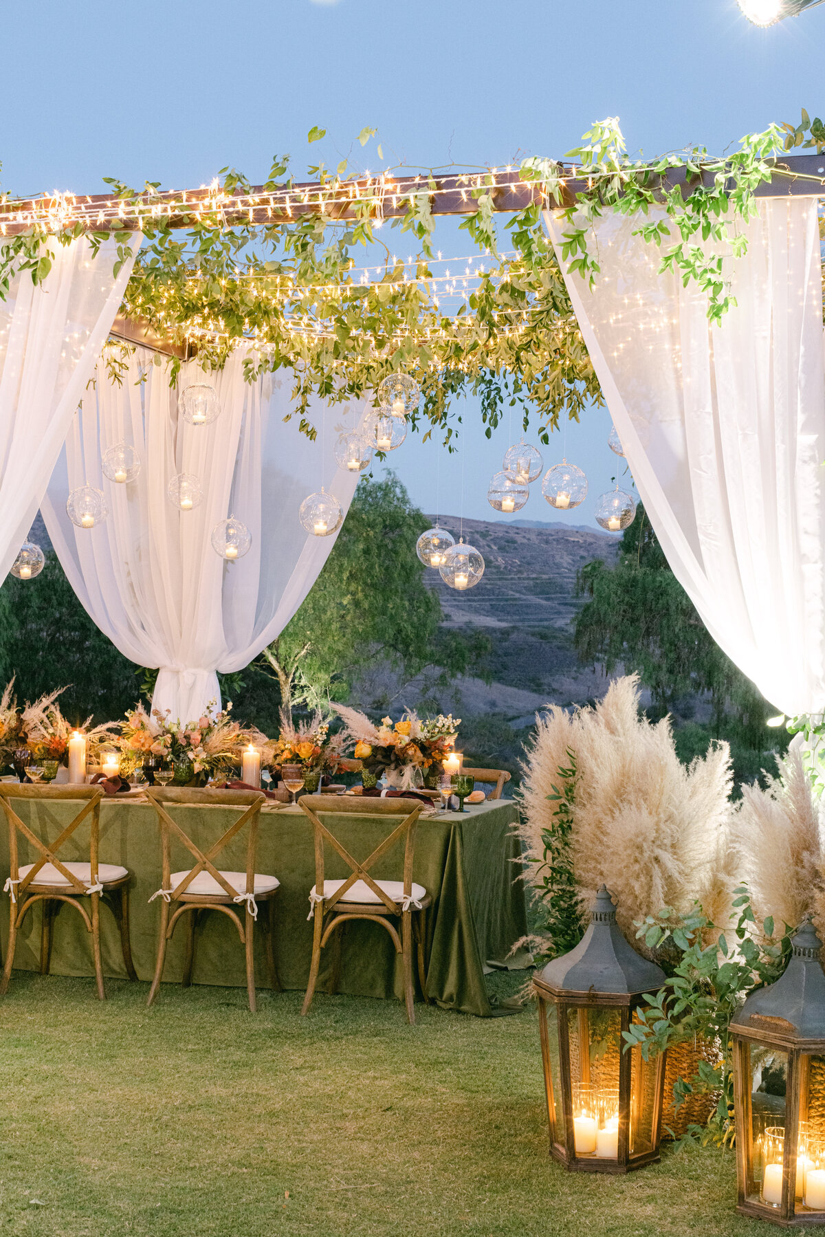 Draped ceremony arch with lanterns at dusk