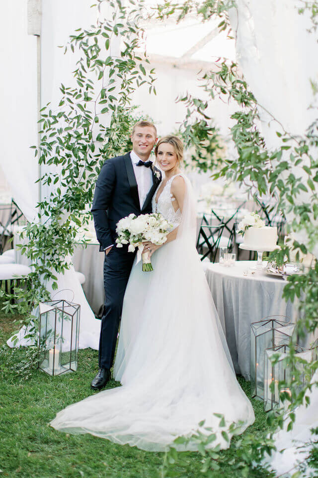 Bride and groom beneath climbing white roses
