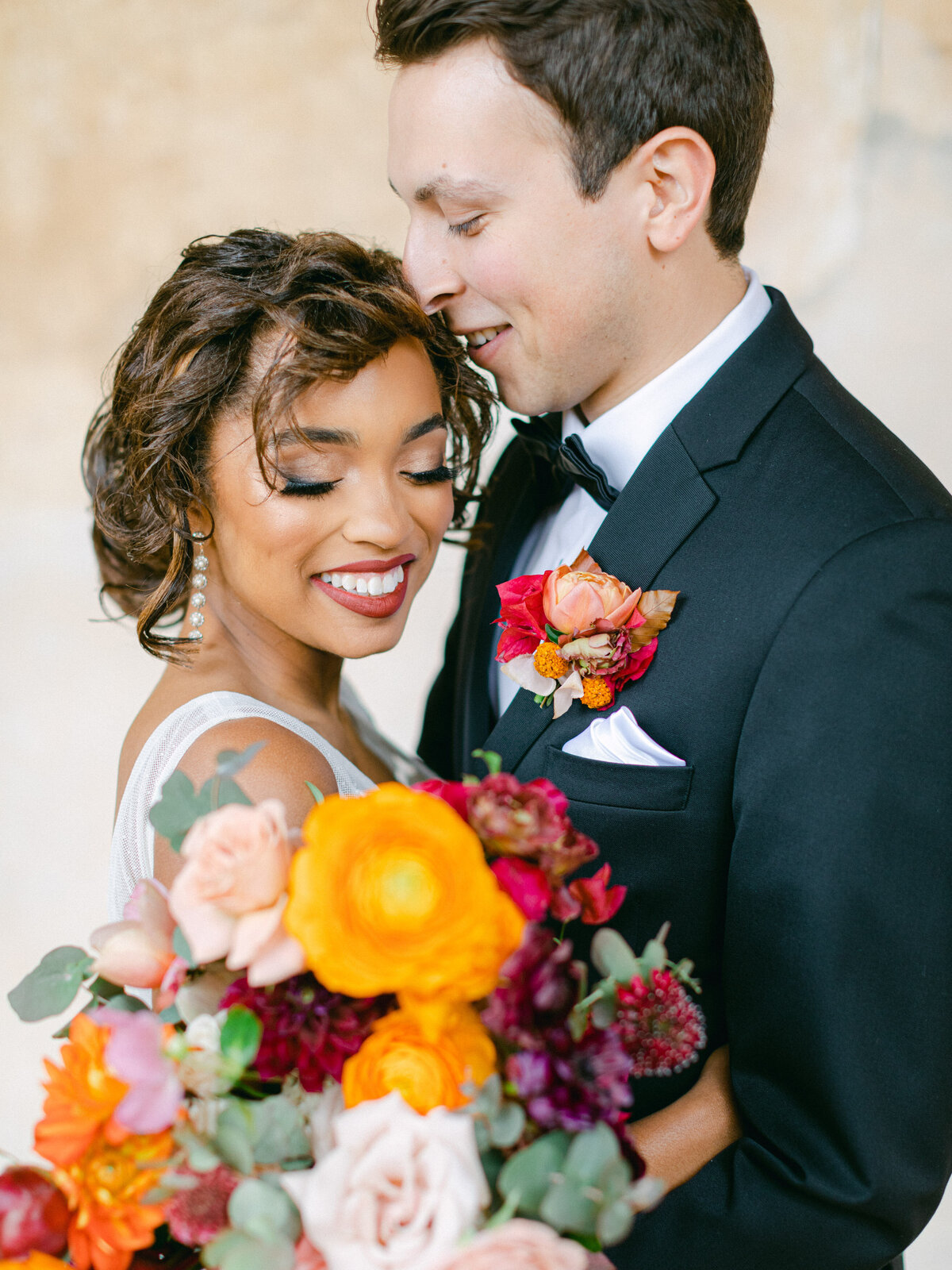 Groom kissing his bride, marigold and ranunculus in hand