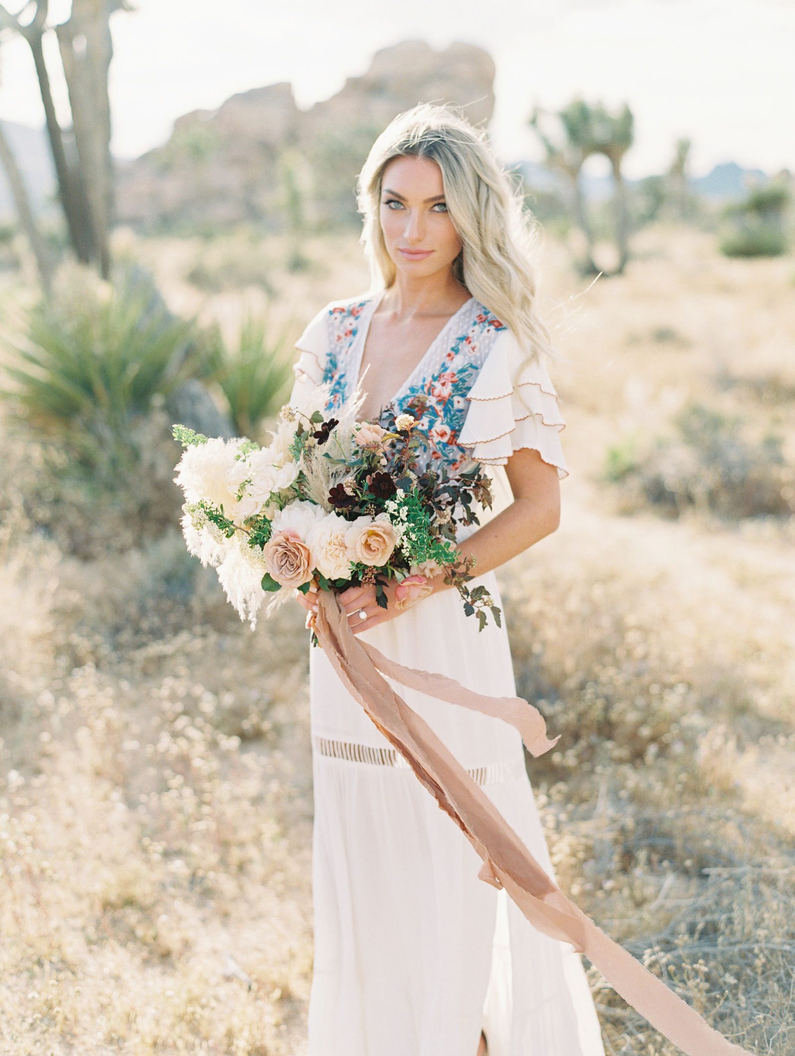A desert bride with a garden bouquet and trailing ribbon in Joshua Tree