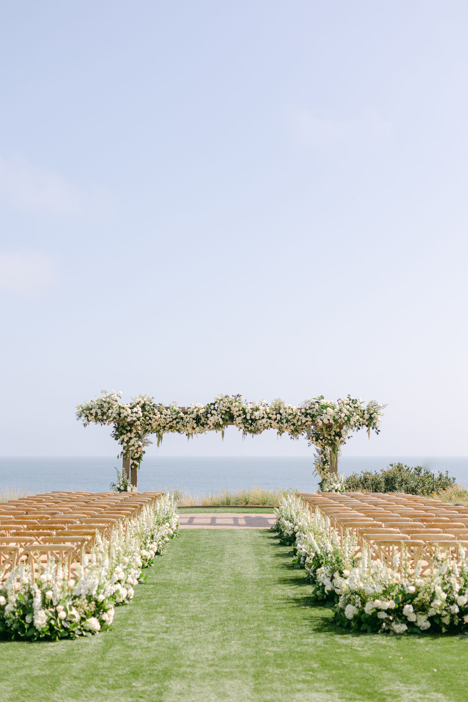 The ceremony arch above the Pacific, an aisle lined in white