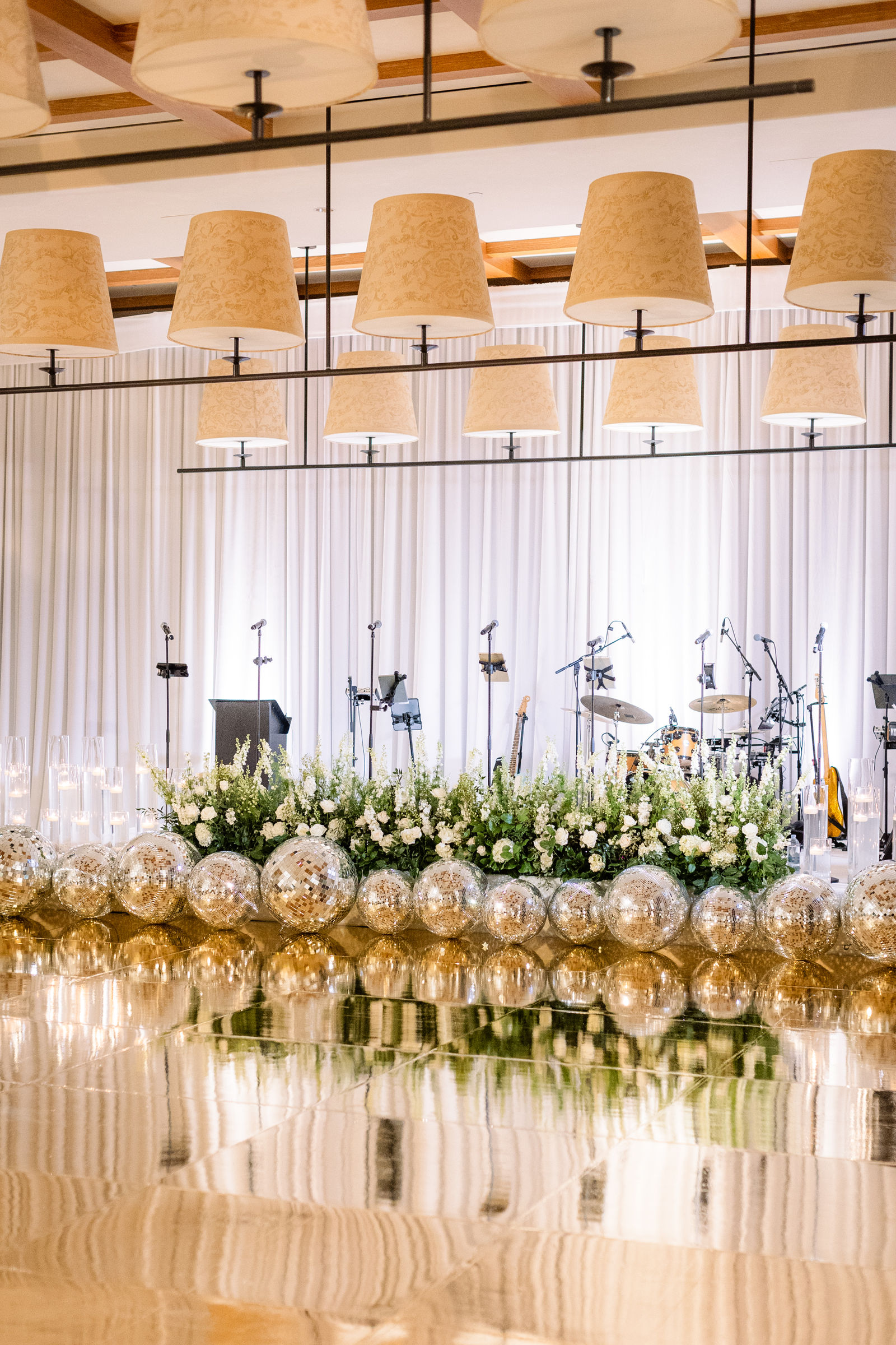 The band stage dressed in white, florals and mirrored spheres