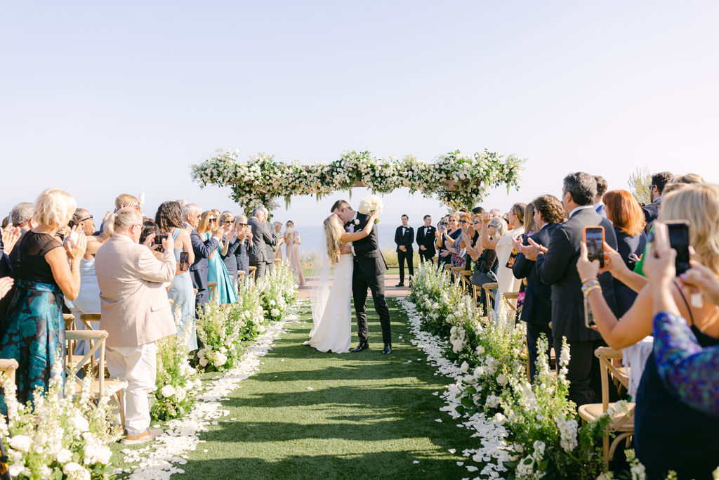 The recessional beneath a white floral arch at Terranea