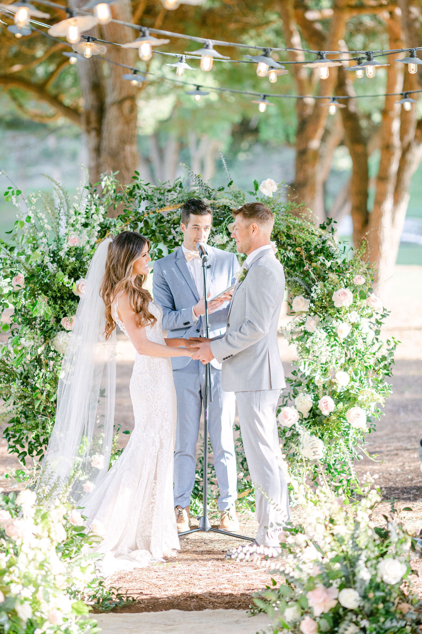 Vows beneath a greenery and white floral arch at The Ranch at Laguna Beach