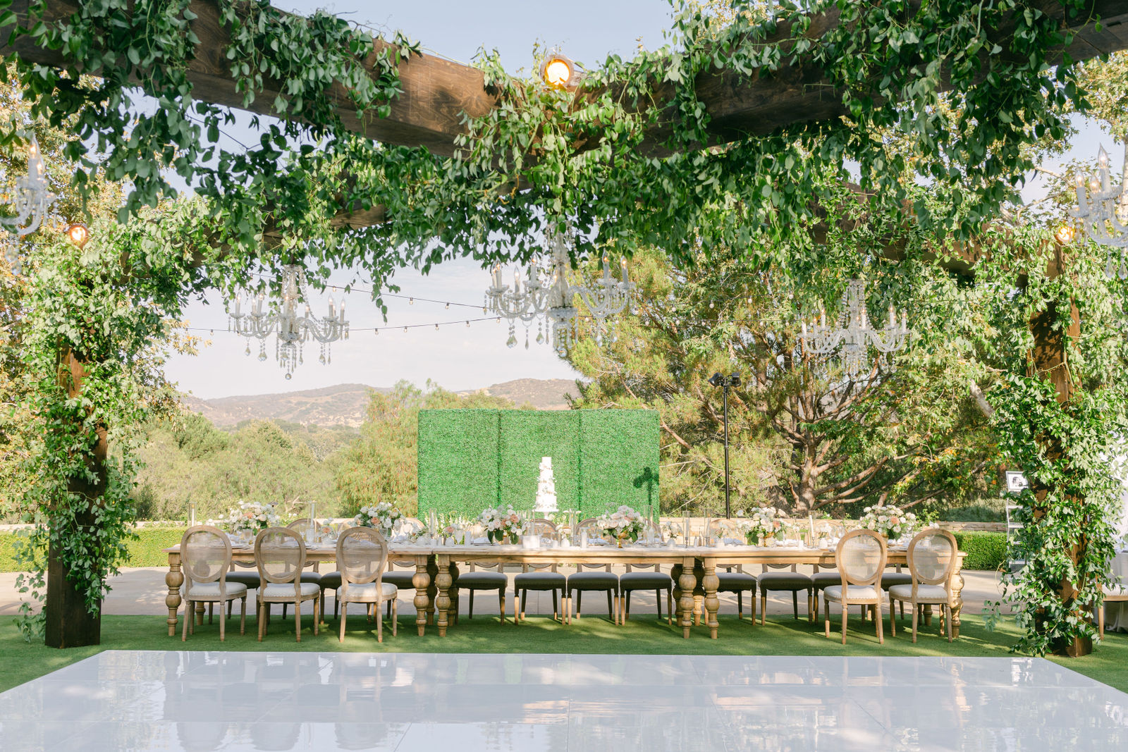 A reception beneath the vine-covered pergola at Shady Canyon Golf Club, chandeliers overhead