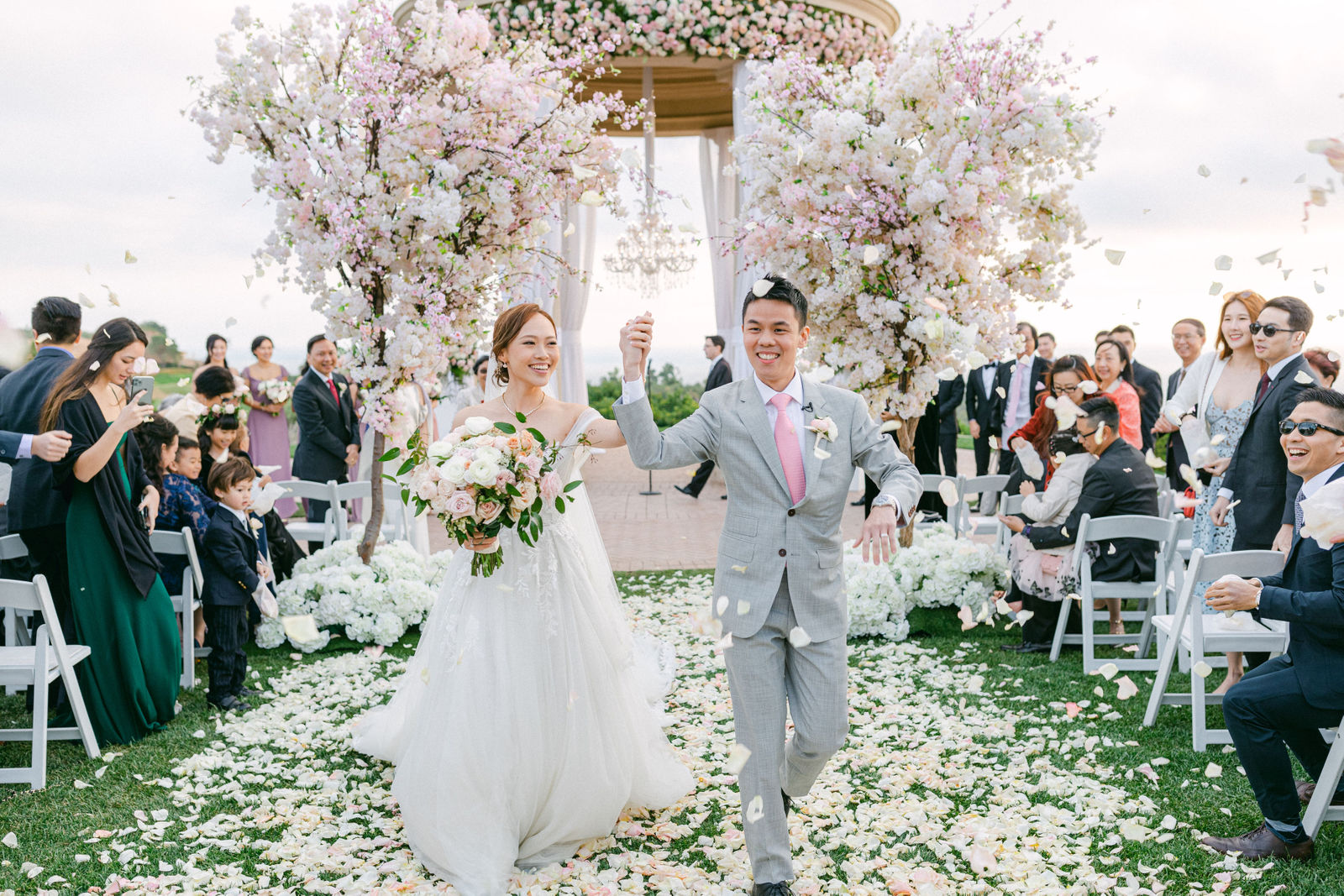 The recessional, arms up, guests on their feet at Pelican Hill
