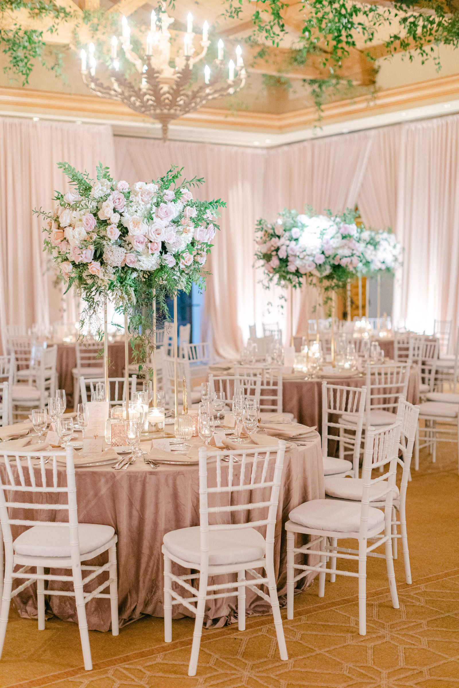 The ballroom in blush, chandeliers and tall floral centerpieces