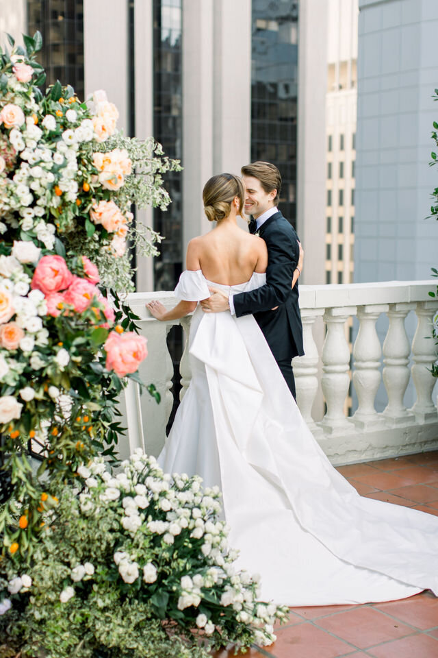 Bride and groom beneath a coral rose arch on a rooftop terrace
